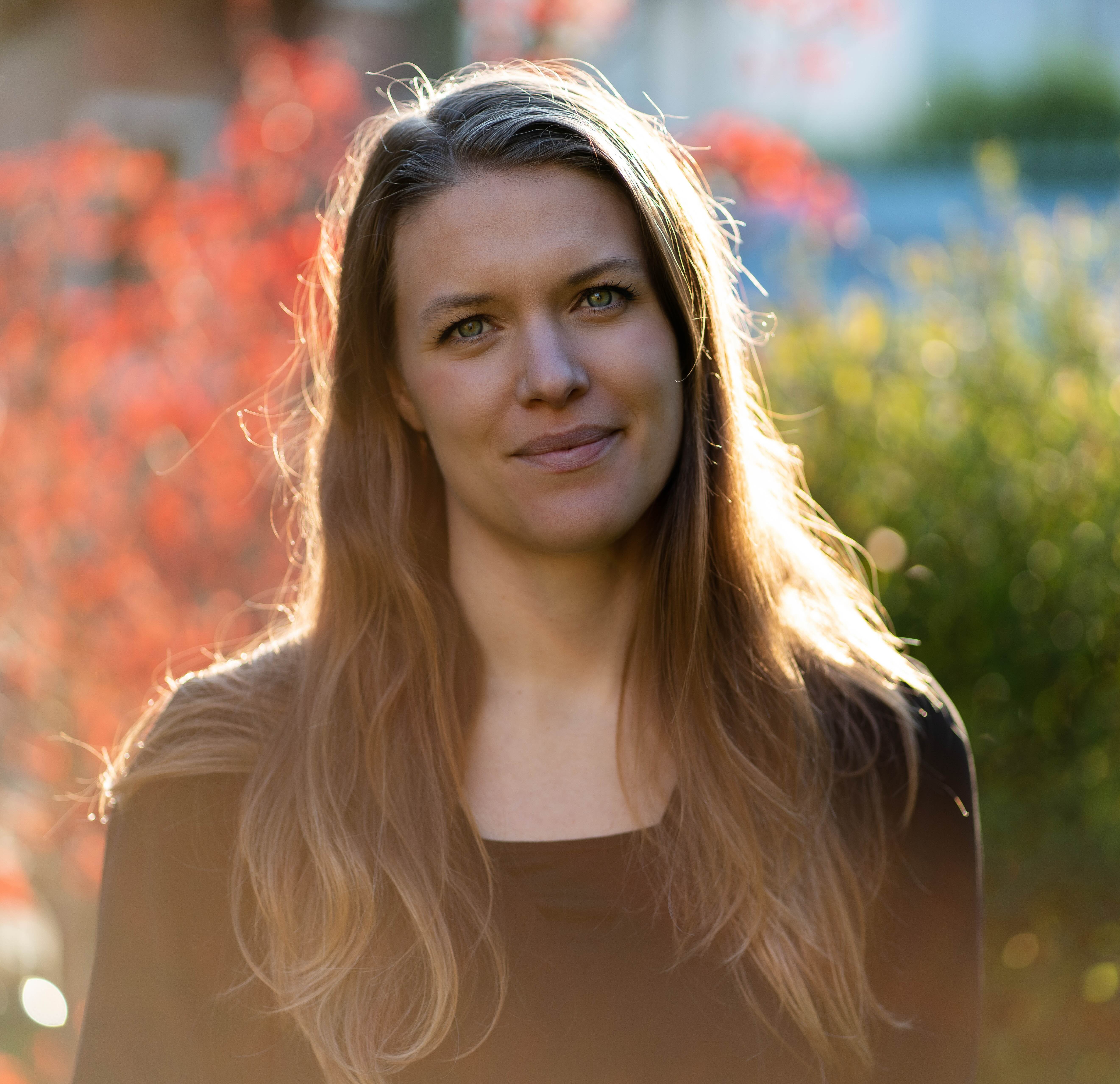 headshot of Laura Wolz with red and green foliage in background